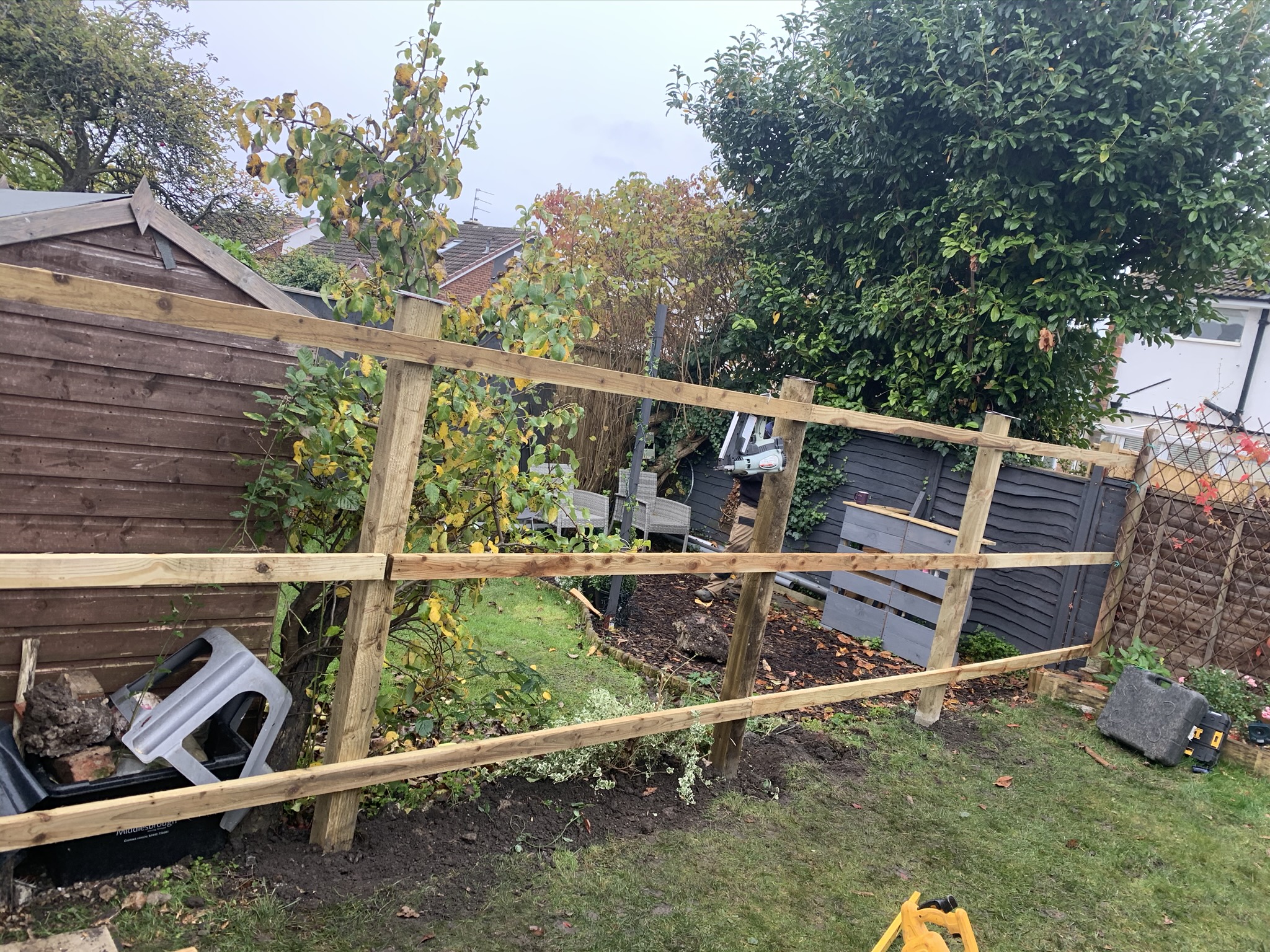 Post-and-rail fence going in along a garden