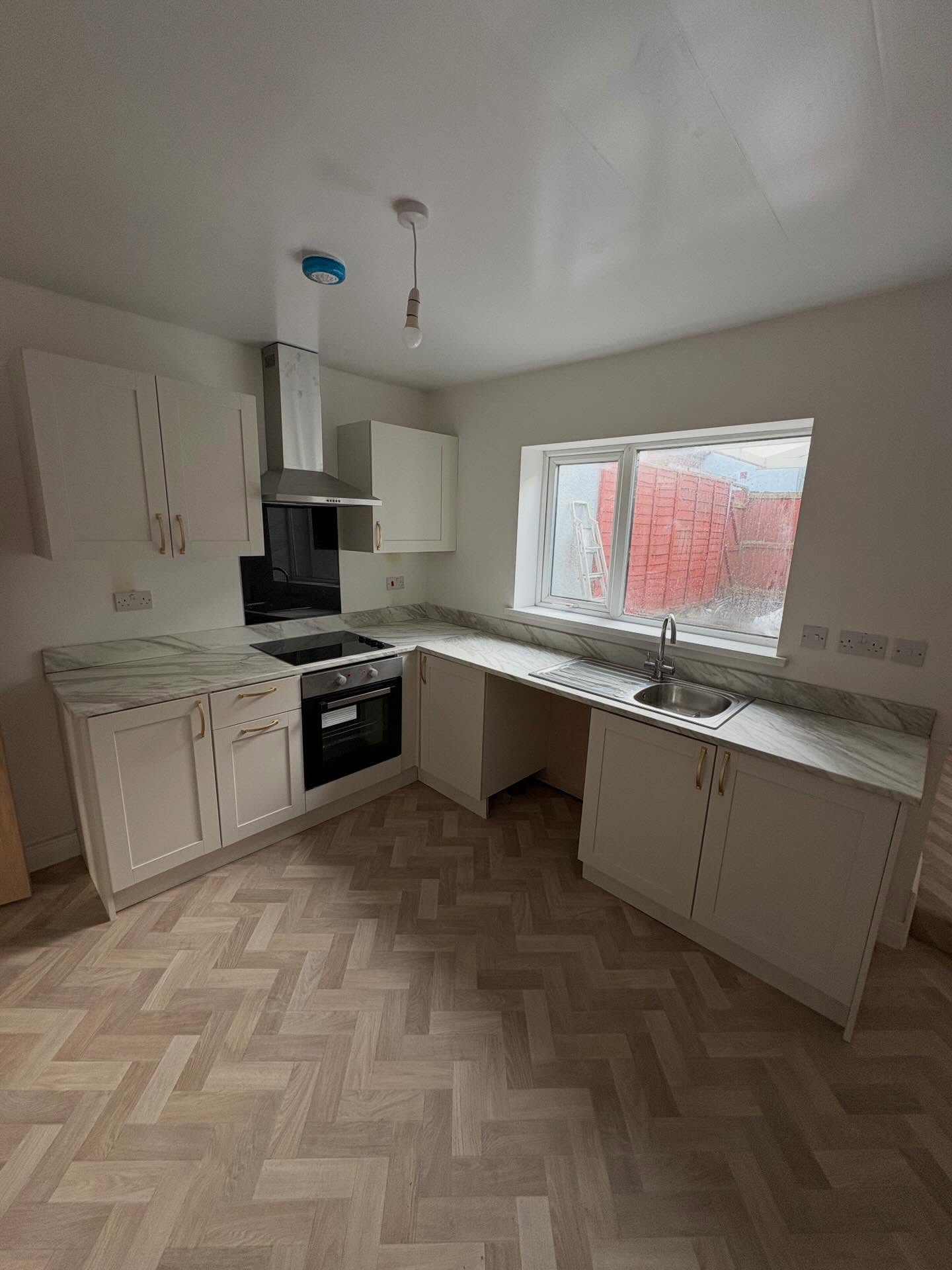 Finished white shaker kitchen with a herringbone floor
